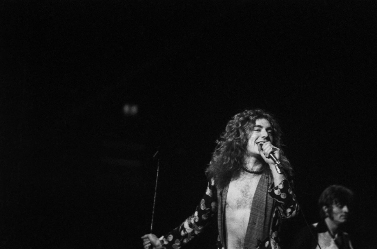 A black and white picture of Robert Plant singing into a microphone.