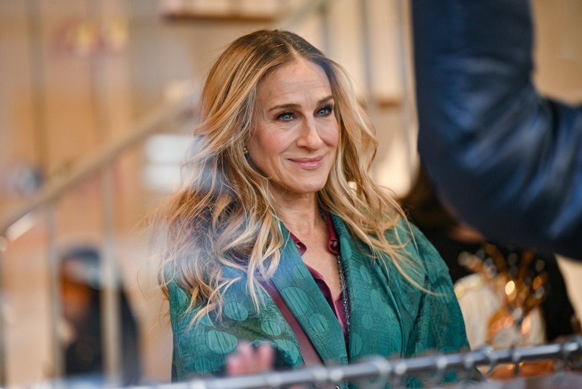 Sarah Jessica Parker is seen on the set of "And Just Like That..." Season 2 the follow up series to "Sex and the City" wearing a green jacket and smiling in the window