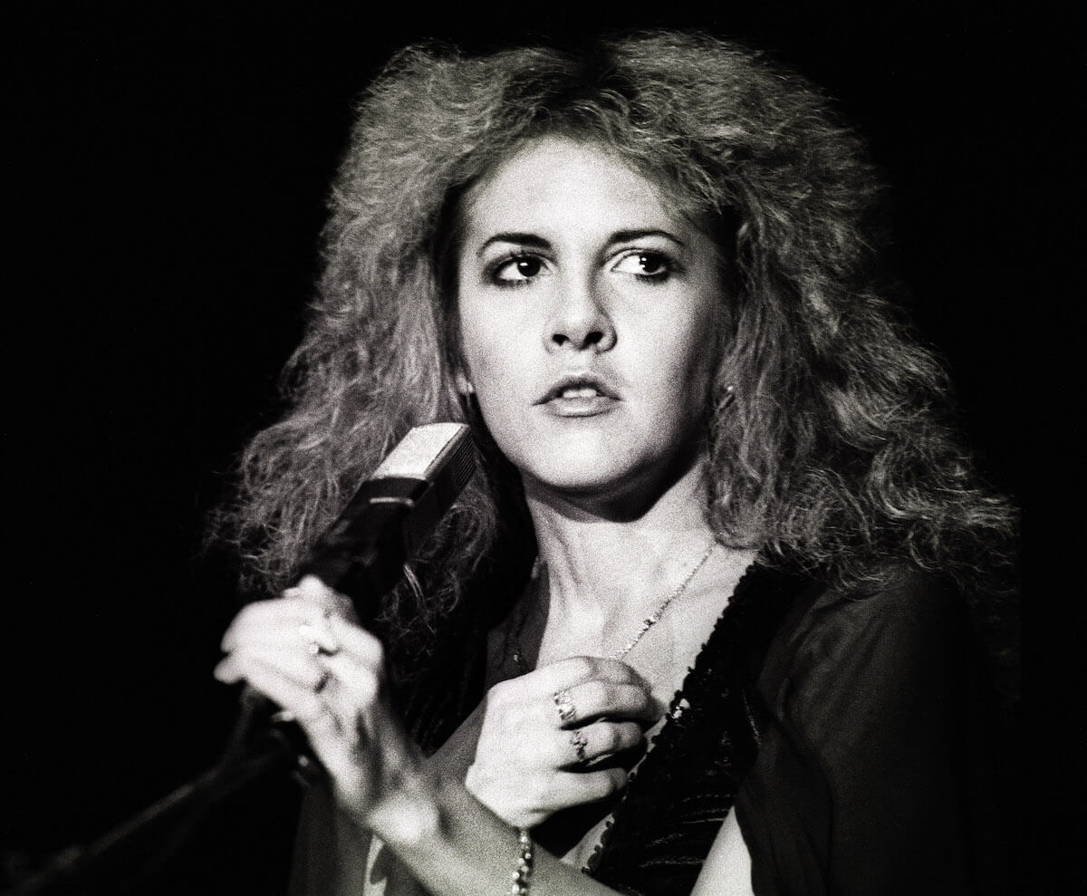 Black and white photo of a young Stevie Nicks holding a microphone.