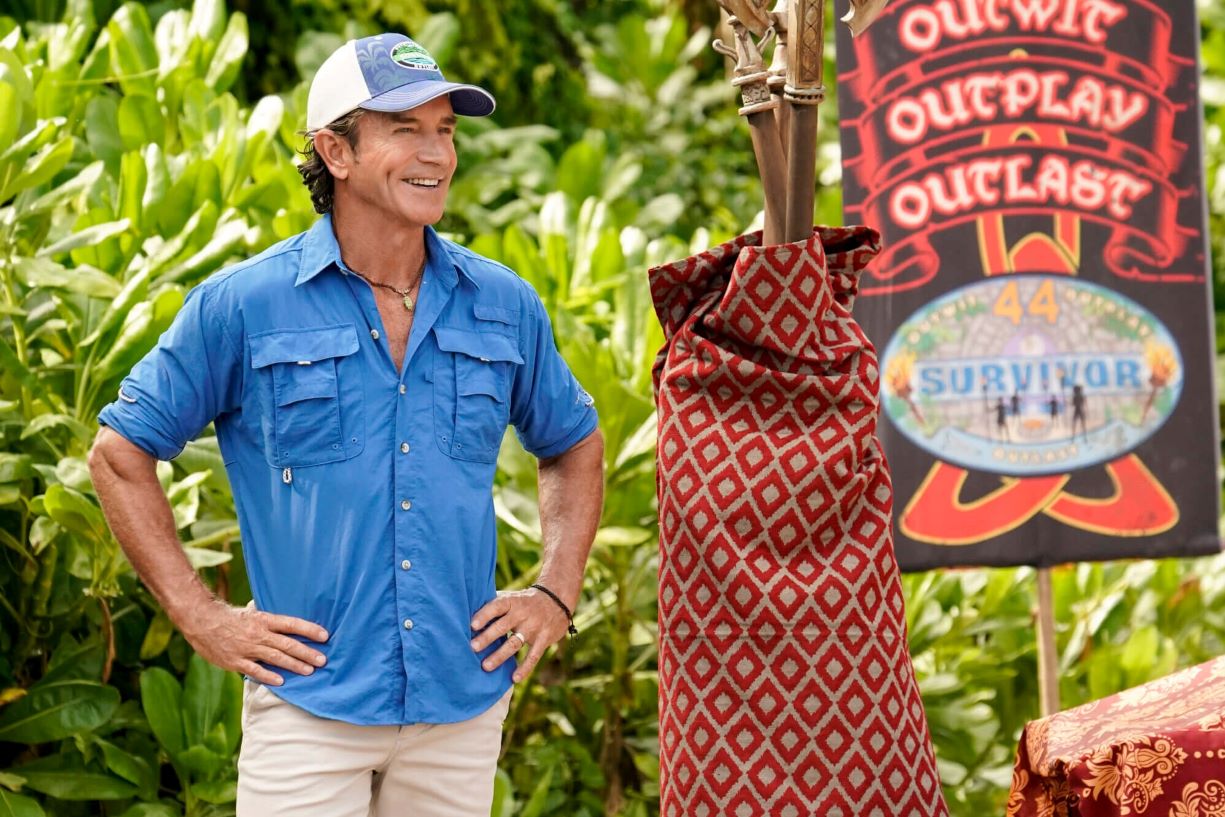 Jeff Probst, who knows all of the 'Survivor 44' spoilers, wears a bright blue safari shirt, white shorts, and a white and blue 'Survivor' hat at an Immunity Challenge in season 44 episode 7.