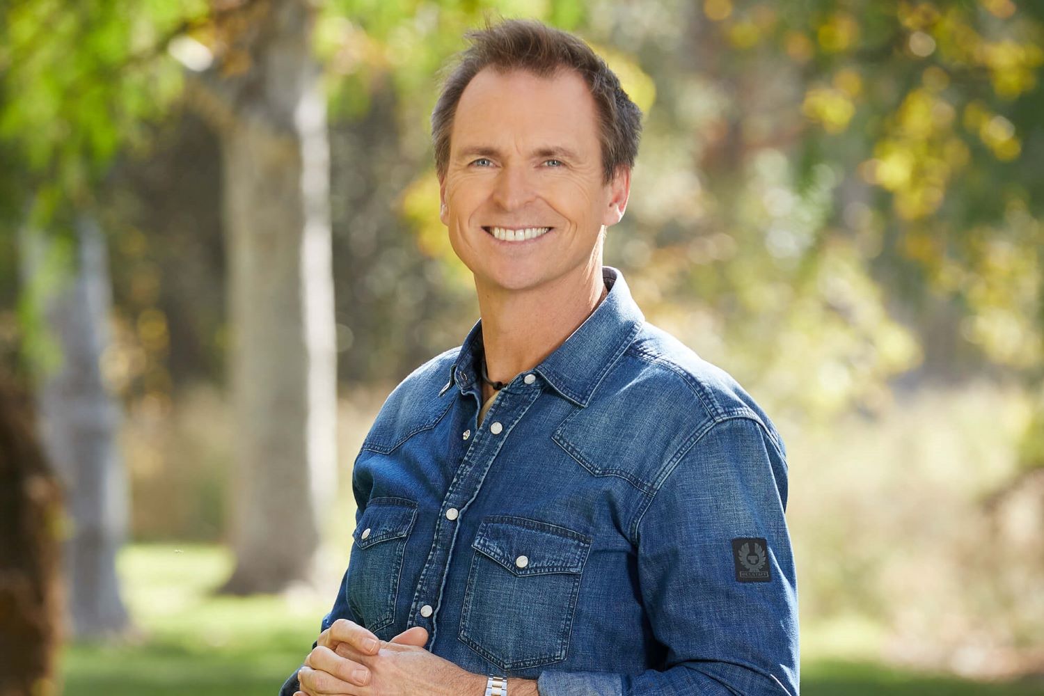 Phil Keoghan, who has hosted every season of 'The Amazing Race,' wears a blue denim button-up shirt.