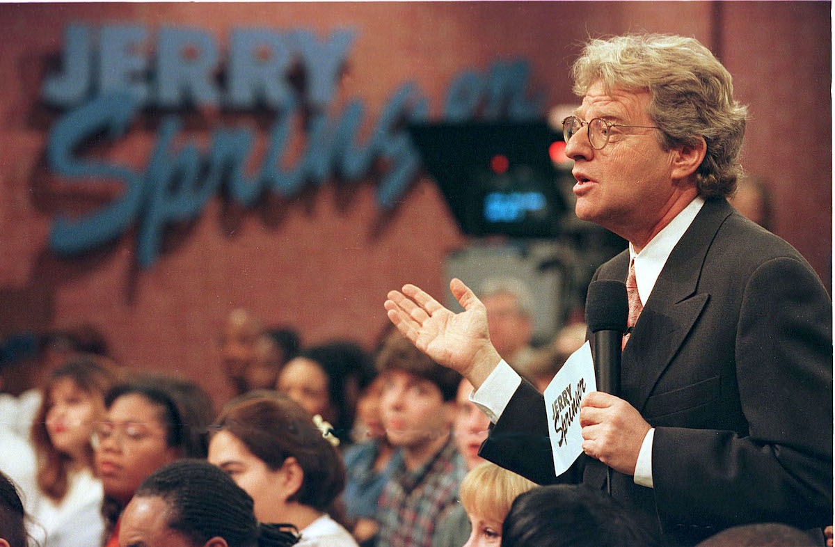 Jerry Springer, holding a microphone and standing in front of an audience during a taping of 'The Jerry Springer Show'