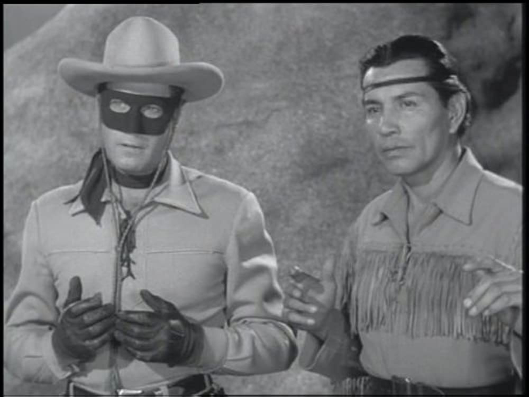 'The Lone Ranger' Clayton Moore as the Lone Ranger and Jay Silverheels as Tonto. The Lone Ranger is holding his hands against his stomach, while Tonto is holding his hands up.