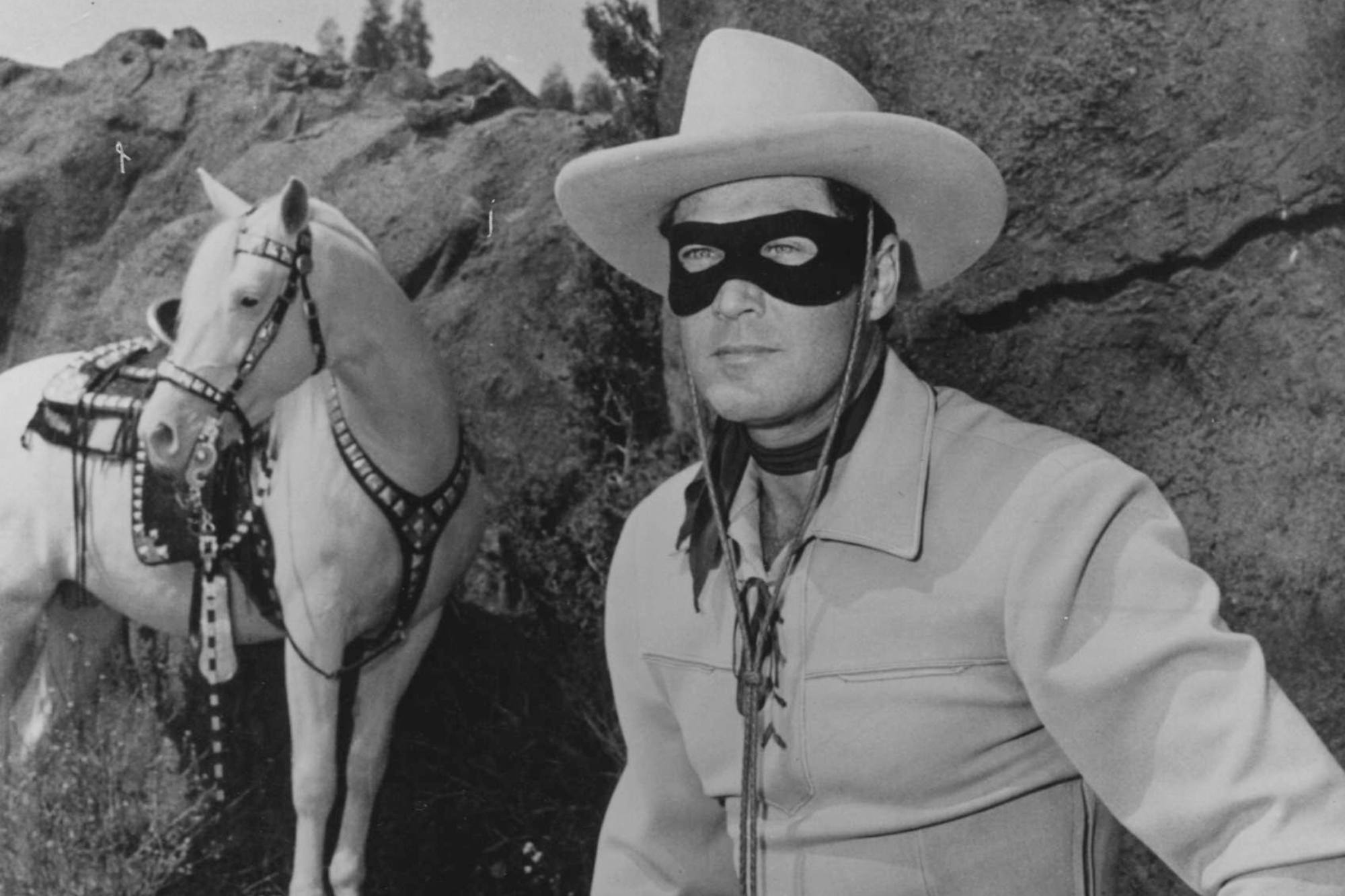 'The Lone Ranger' Season 3 Clayton Moore wearing his Western costume, standing in front of his white horse.