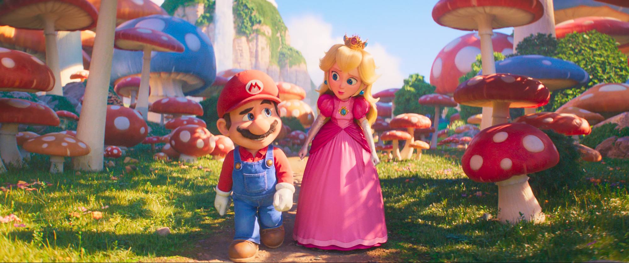 'The Super Mario Bros. Movie' Mario (voiced by Chris Pratt) and Princess Peach (voiced by Anya Taylor-Joy) walking on a path surrounded by grass and large mushrooms, as they look at one another.