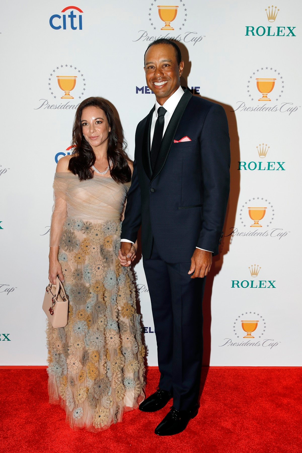 Tiger Woods and Erica Herman hold hands on the red carpet during the Presidents Cup Gala