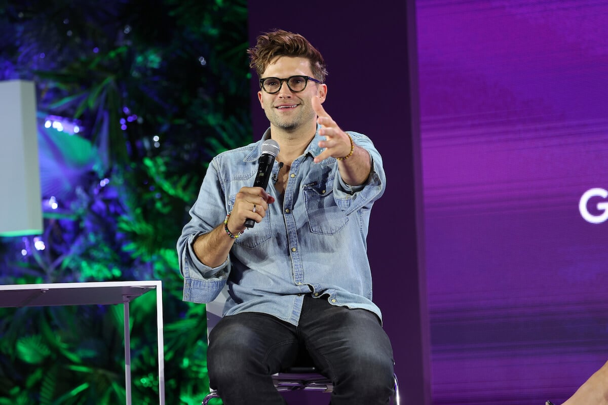 "Vanderpump Rules" star Tom Schwartz holds a microphone while seated on stage.