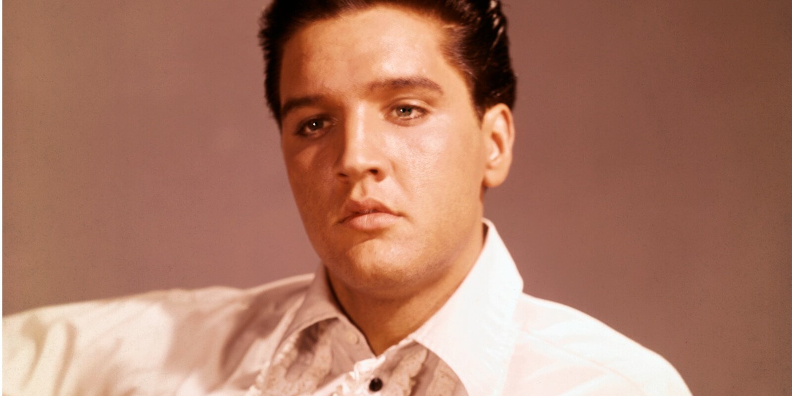 Elvis Presley photographed playing the guitar.