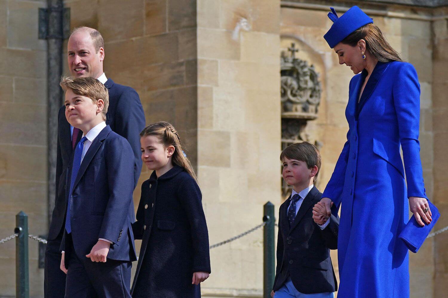 Kate Middleton dressed in vibrant blue looks at son Prince Louis with pride as they walk with Prince William Prince George, and Princess Charlotte