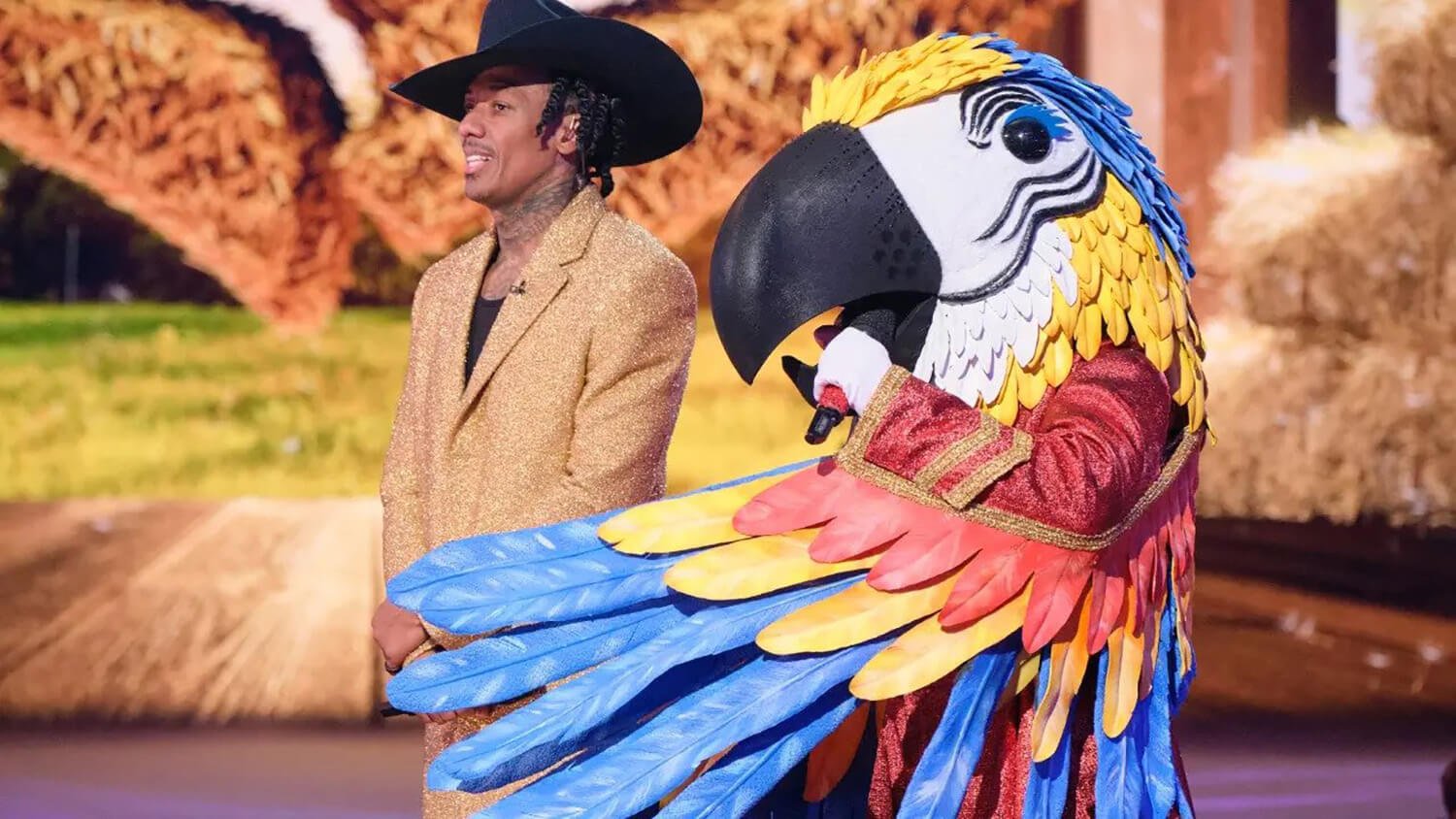 Nick Cannon stands next to Macaw on The Masked Singer Season 9's Country Night