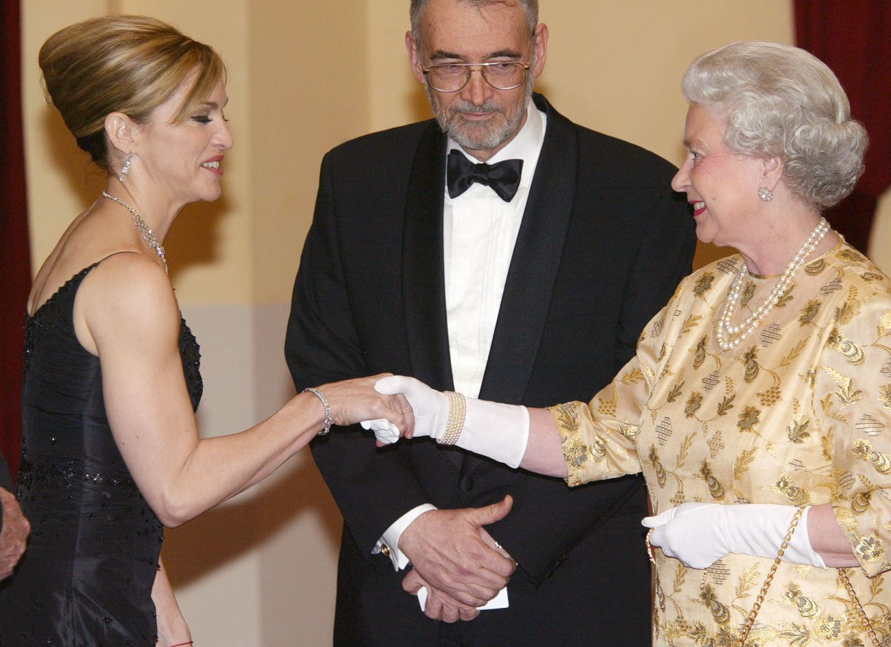 Madonna shakes hands with Queen Elizabeth II while producer Michael Wilson watches. 