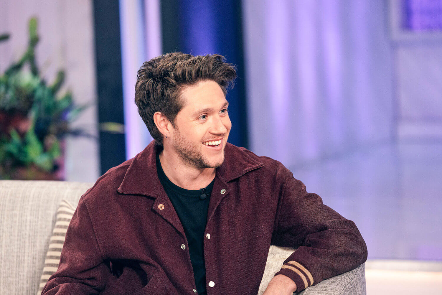 Niall Horan smiles in his seat on The Kelly Clarkson Show, where he and Clarkson discussed The Voice and his time on The X Factor.
