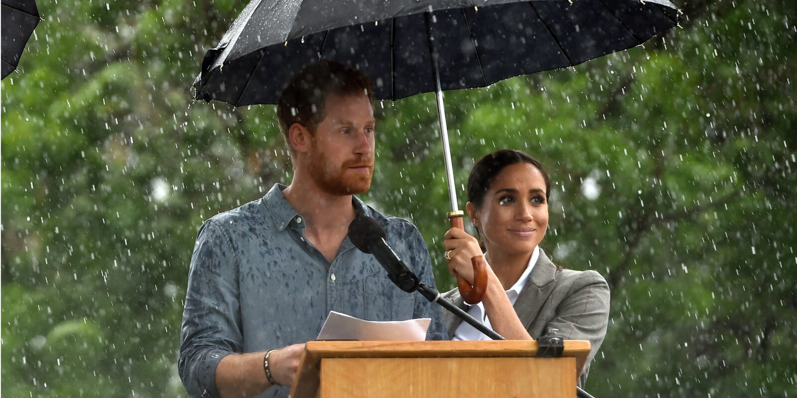 Prince Harry and Meghan Markle stand under an umbrella in 2018 in Australia.