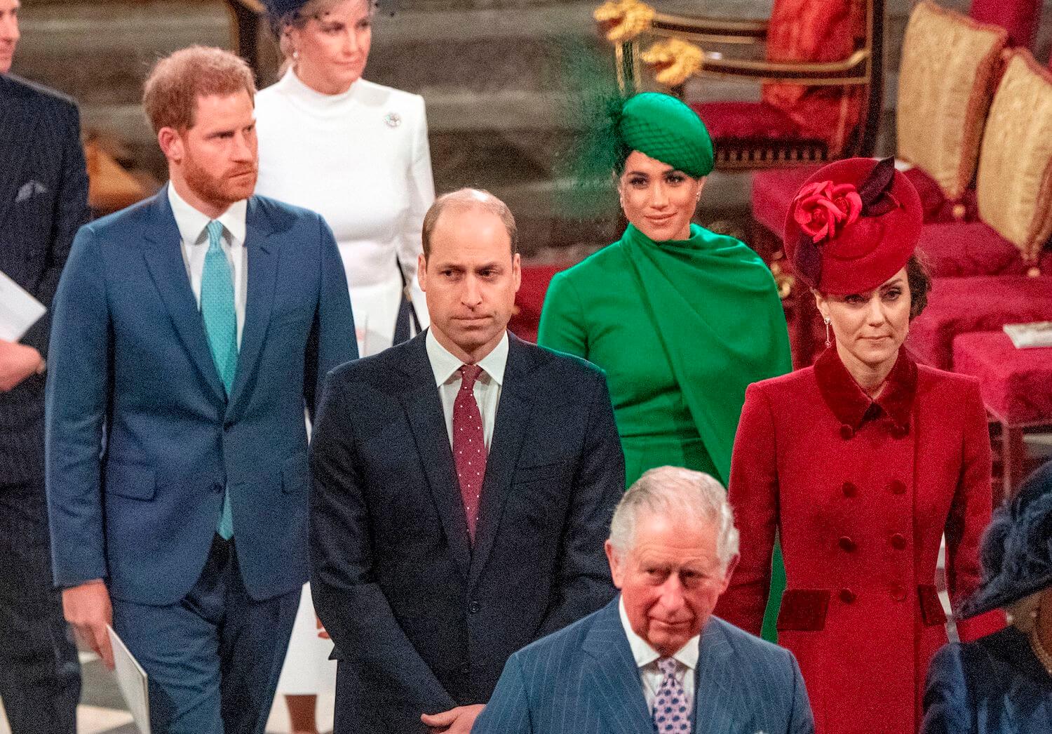Prince Harry wears a suit and walks with Meghan Markle dressed in green with other members of the royal family