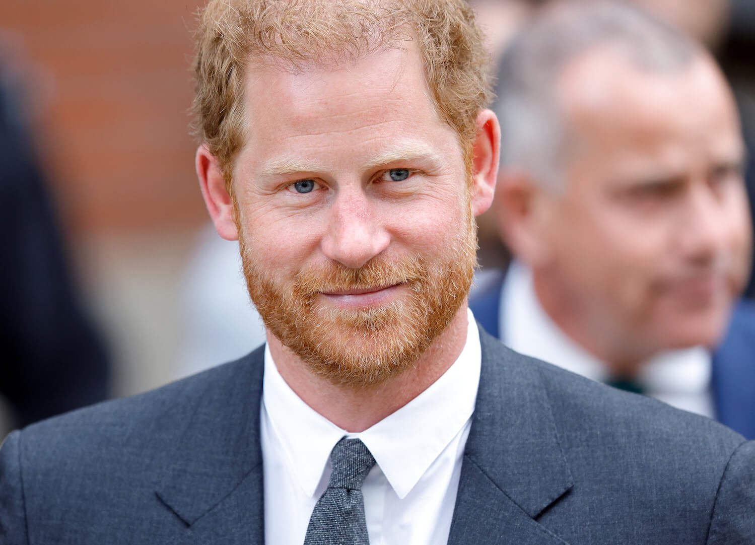 Prince Harry smiles slightly while wearing a suit and tie
