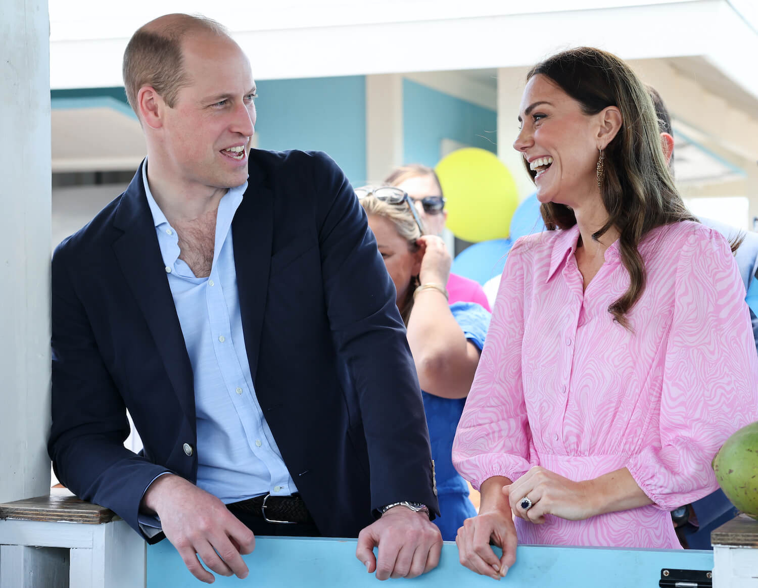 Prince William looks at Kate Middleton, dressed in a pink shirt and smiling