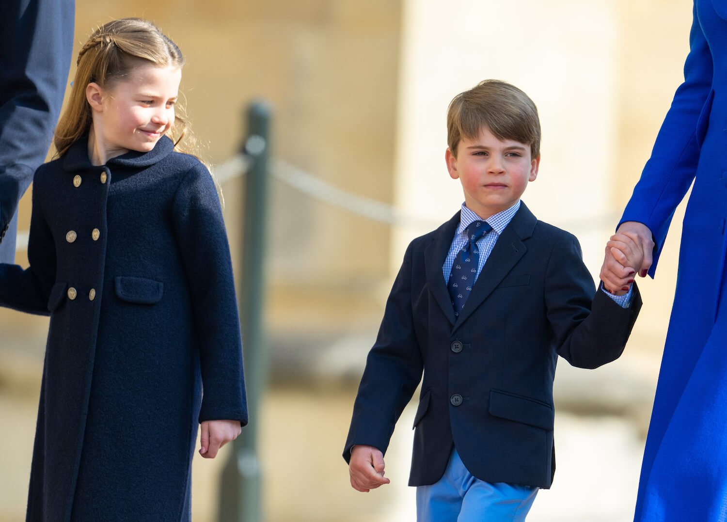 Princess Charlotte smiles as she walks next to Prince Louis, who holds mom Kate Middleton's hand