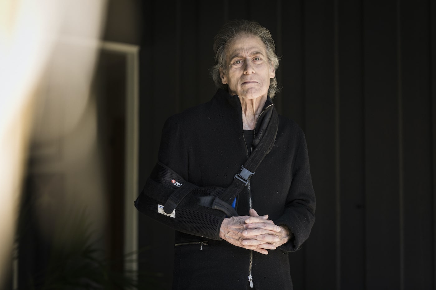 Richard Lewis poses wearing an arm brace