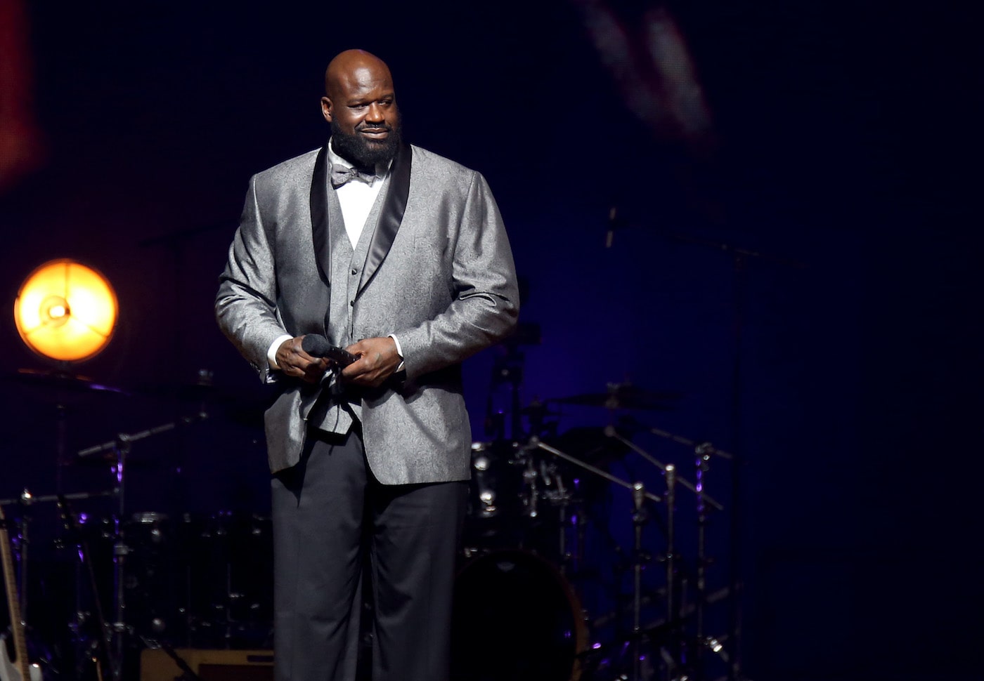 Shaquille O'Neal stands on stage in a tuxedo