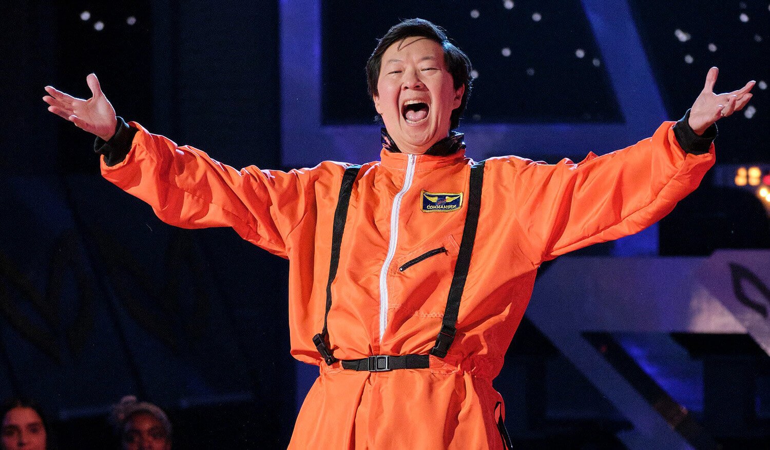 Ken Jeong wears an orange space suit with his arms spread wide on The Masked Singer Season 9's Space Night