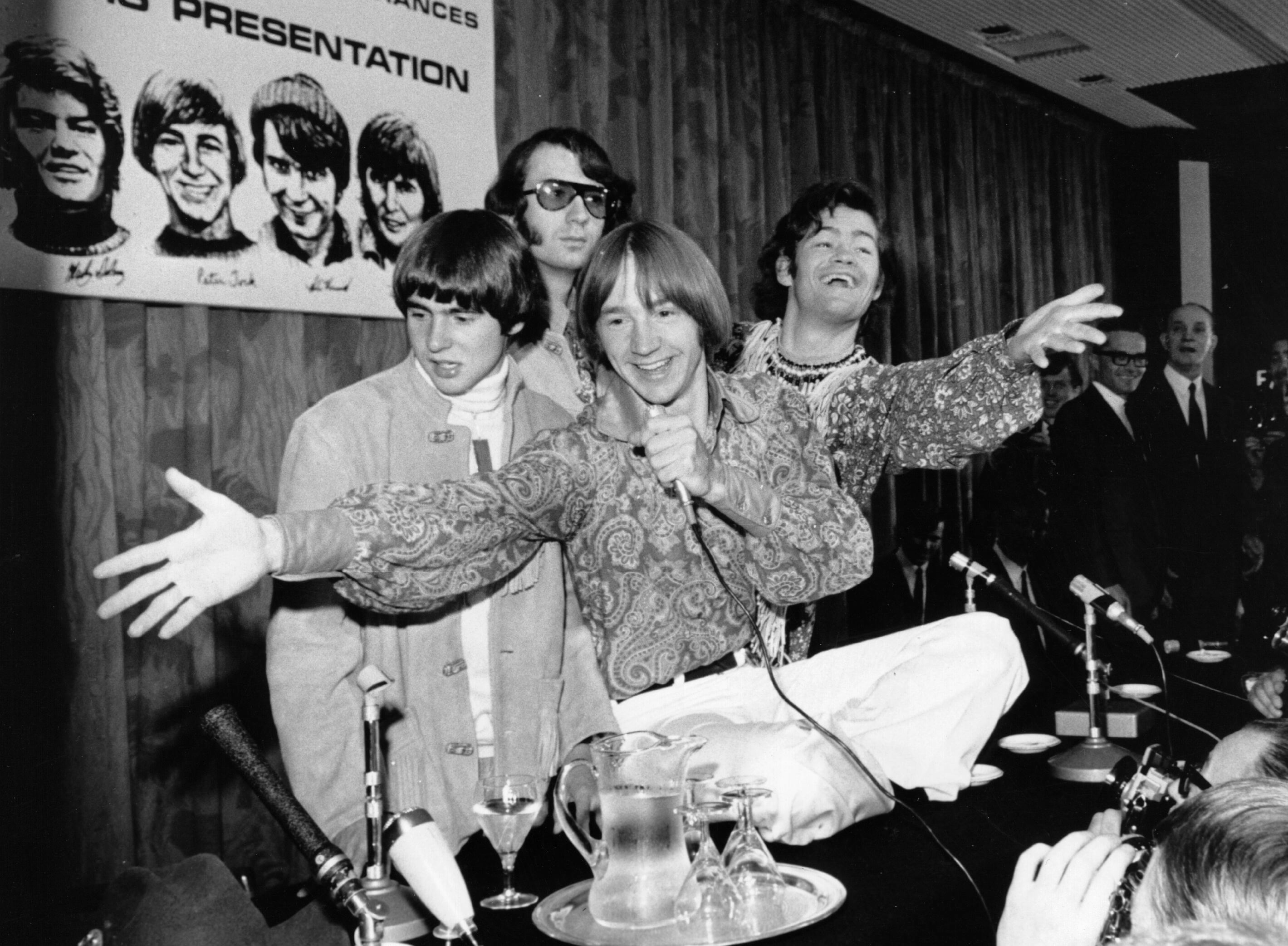 All members of The Monkees near a poster