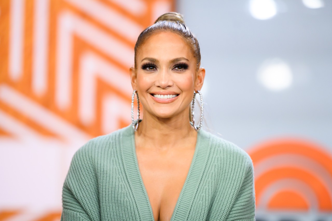 Jennifer Lopez smiles while wearing a seafoam green sweater. 