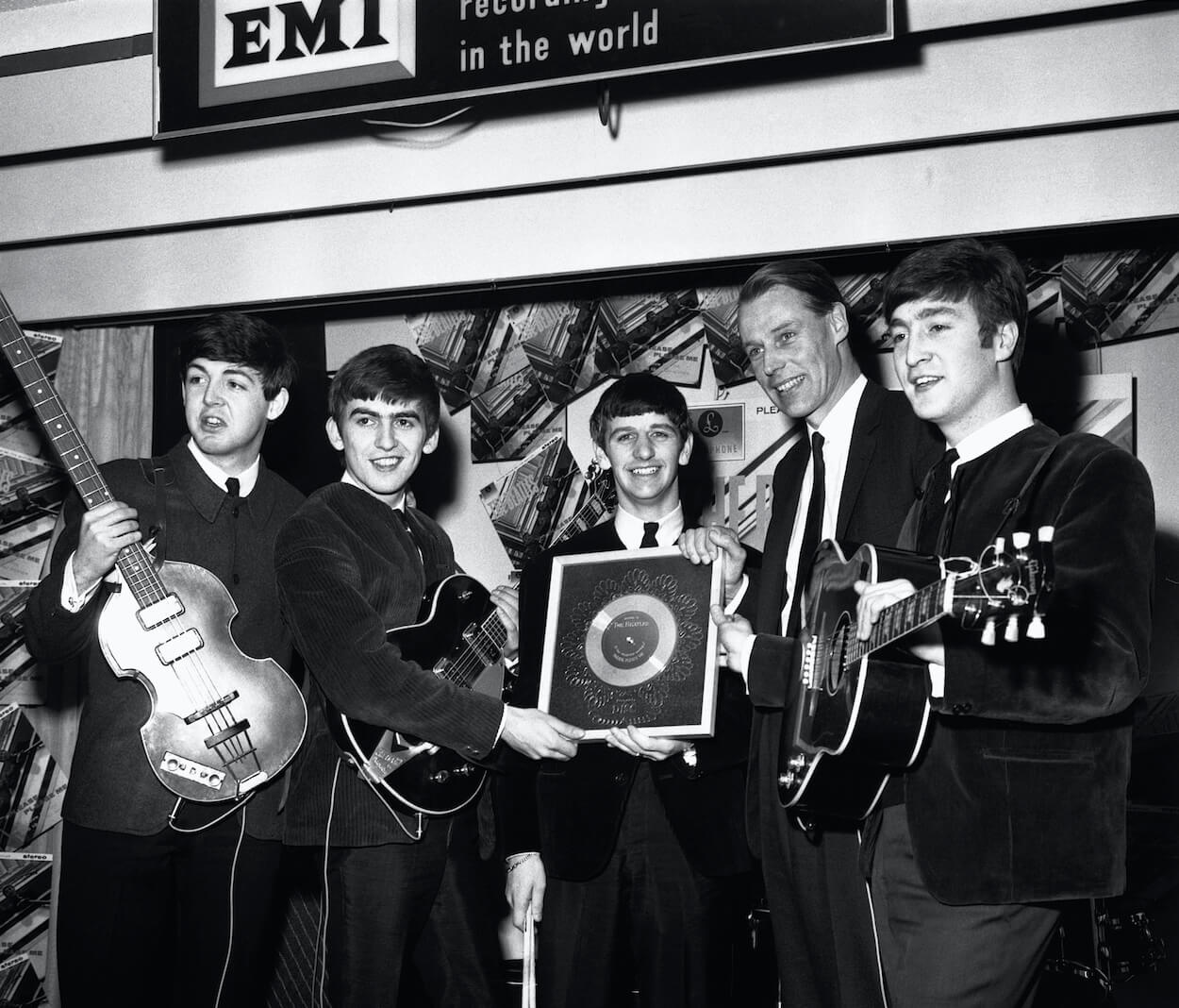 Paul McCartney, George Harrison, Ringo Starr, George Martin, and John Lennon celebrating the success of The Beatles' 'Please Please Me' single.