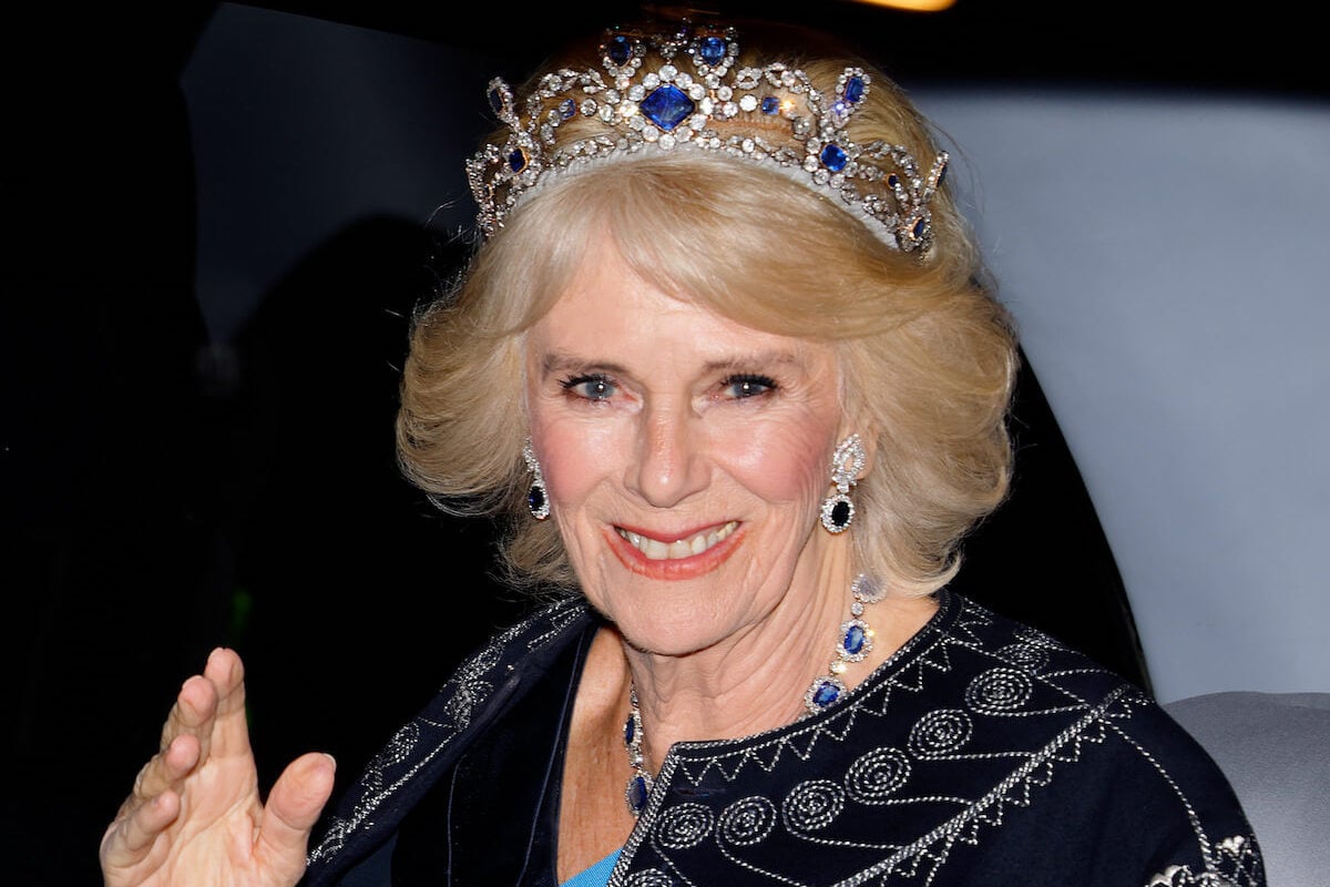 Camilla Parker Bowles, who will wear a repurposed Queen Mary Crown to the coronation, waves wearing a crown