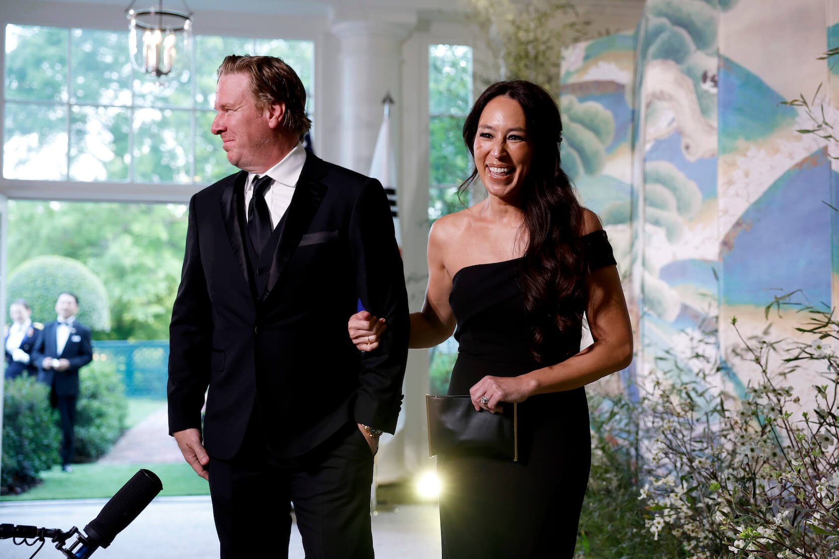Chip and Joanna Gaines from 'Fixer Upper' in black formal attire walking arm in arm and smiling