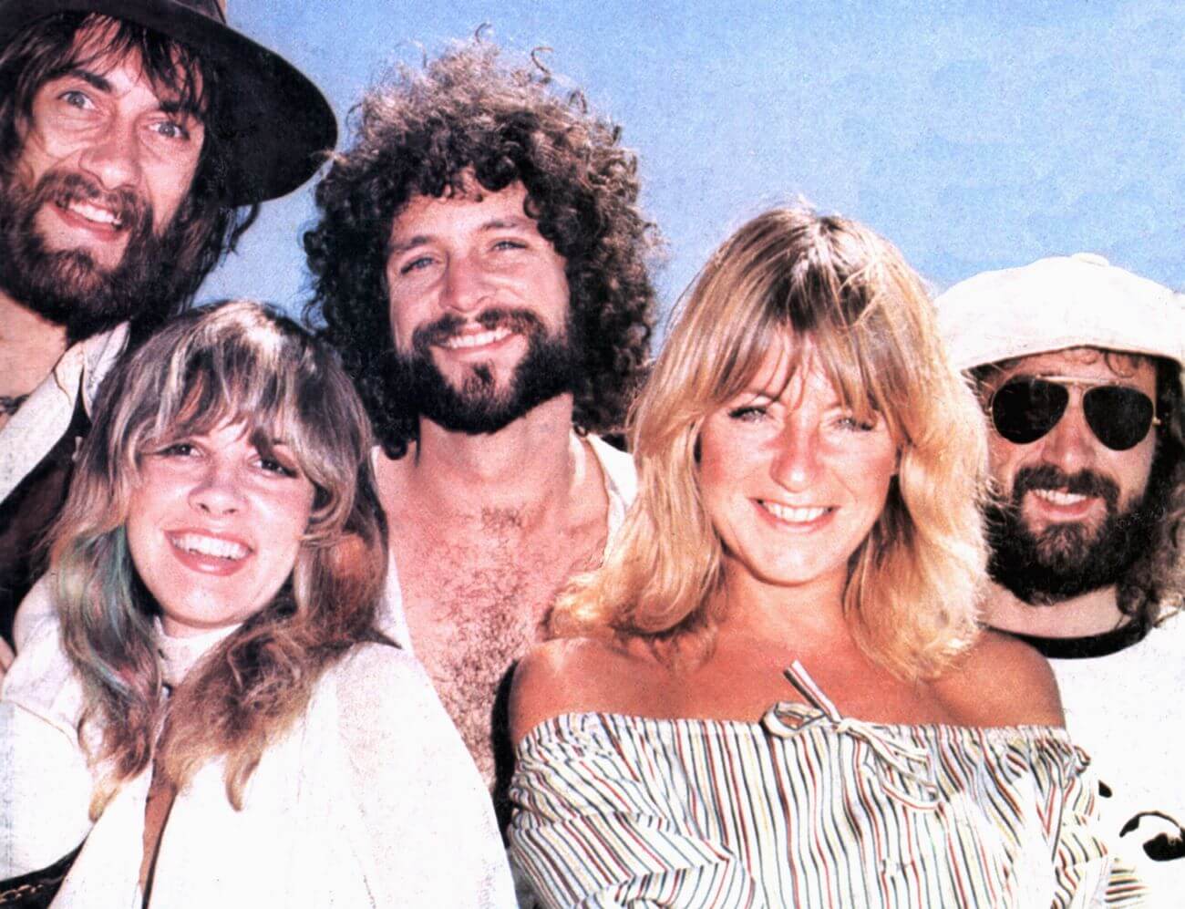 Mick Fleetwood, Stevie Nicks, Lindsey Buckingham, Christine McVie, and John McVie smile against a blue background.
