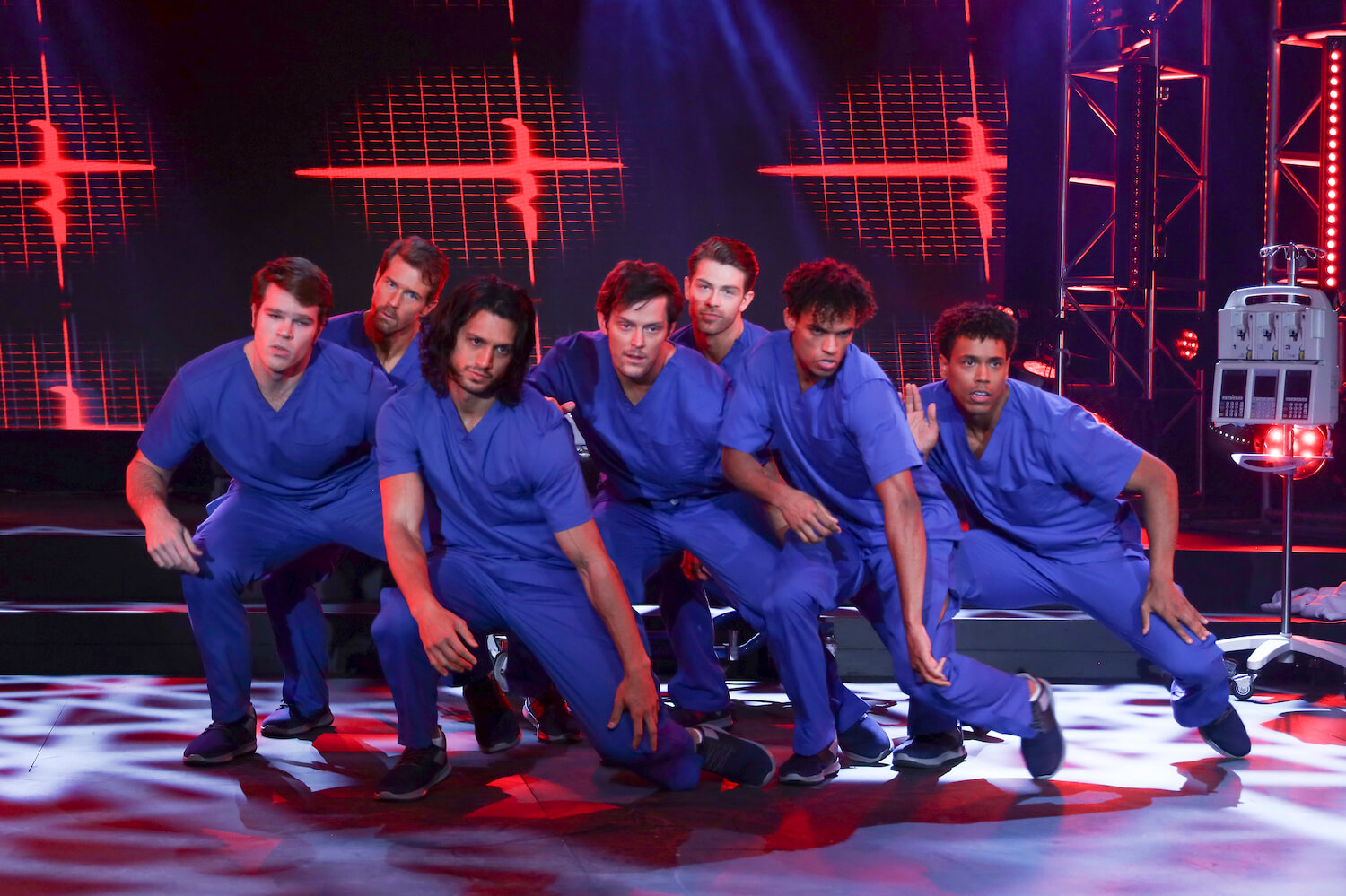 Cast members in 'General Hospital' wearing blue scrubs and kneeling