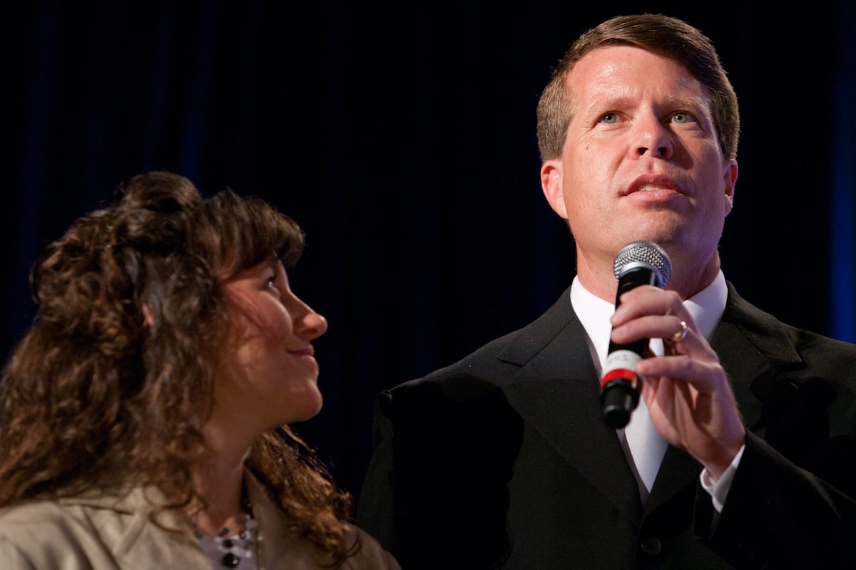 Michele Duggar looking at Jim Bob Duggar, who is holding a microphone