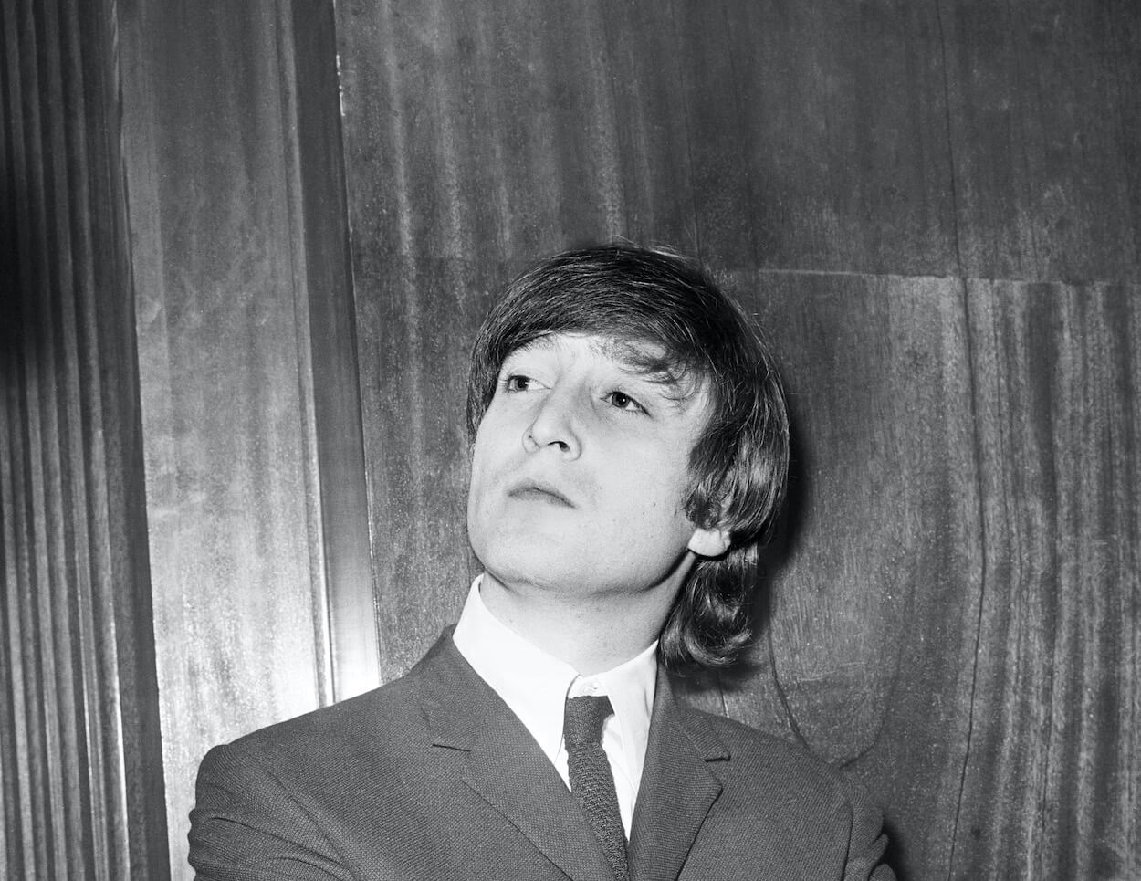 Beatles member John Lennon looking to his right while wearing a suit during a pre-concert press conference in 1964.