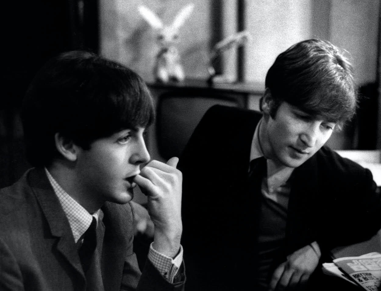 Paul McCartney and John Lennon seated together in late 1963.