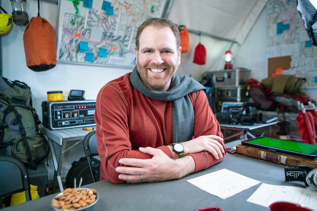 'Expedition Unknown' host Josh Gates smiling and wearing a scarf 