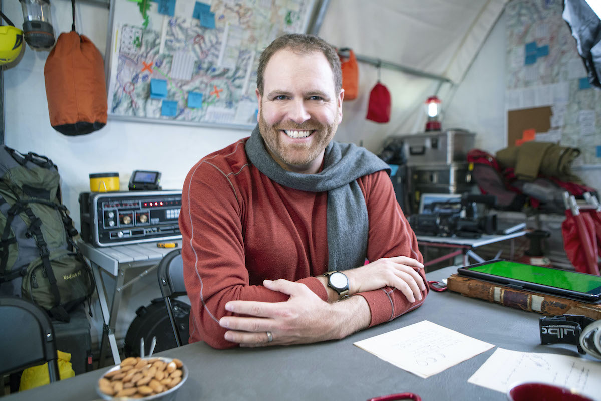 'Expedition Unknown' host Josh Gates smiling and wearing a scarf 