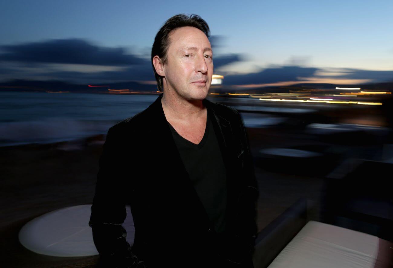 Julian Lennon wears black and stands outside in the evening.