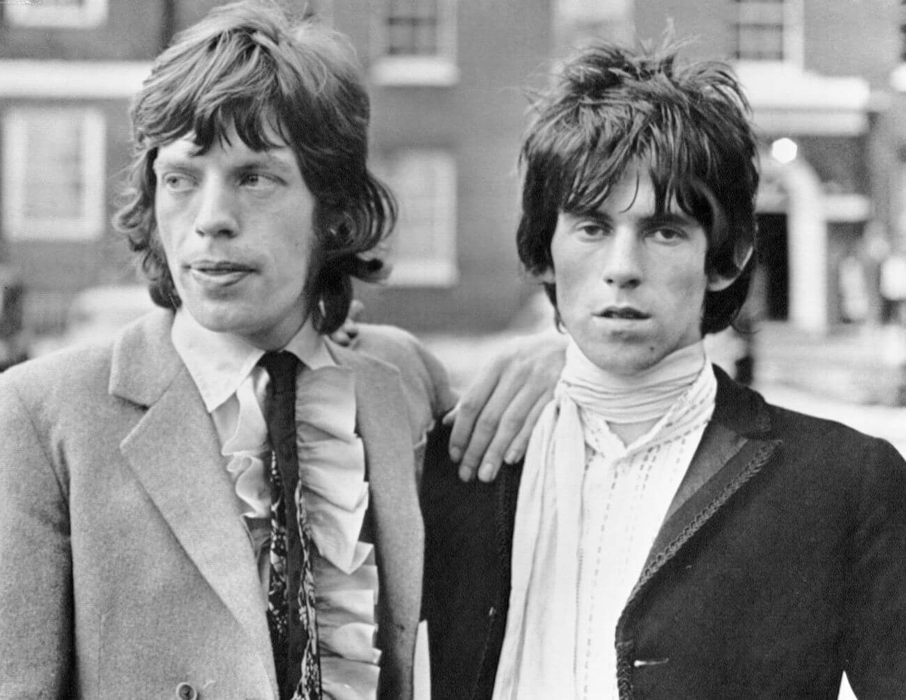 A black and white picture of Mick Jagger standing with his hand on Keith Richards' shoulder.