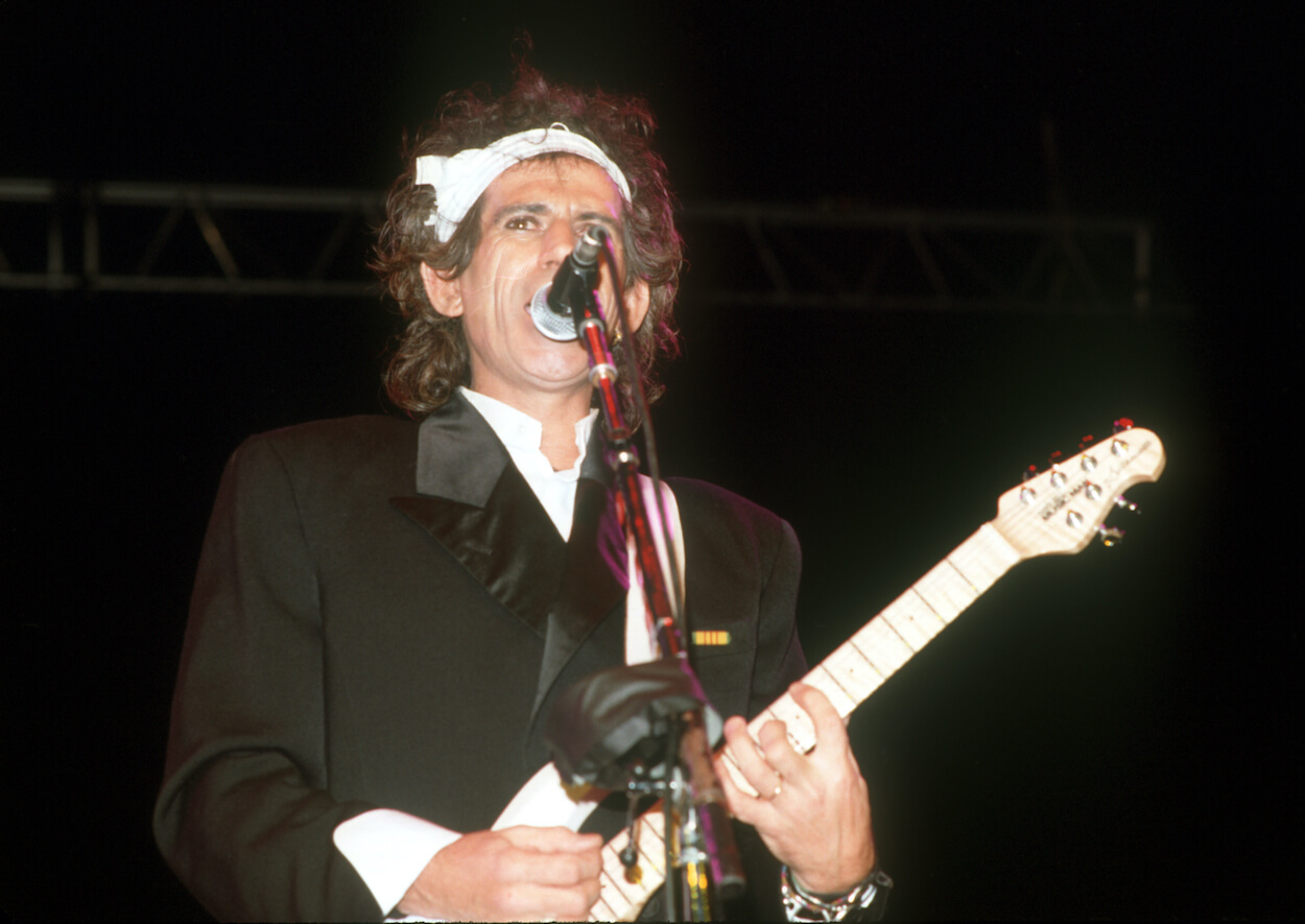 Rolling Stones guitarist Keith Richards wearing a black suit and headband during a 1988 solo performance.