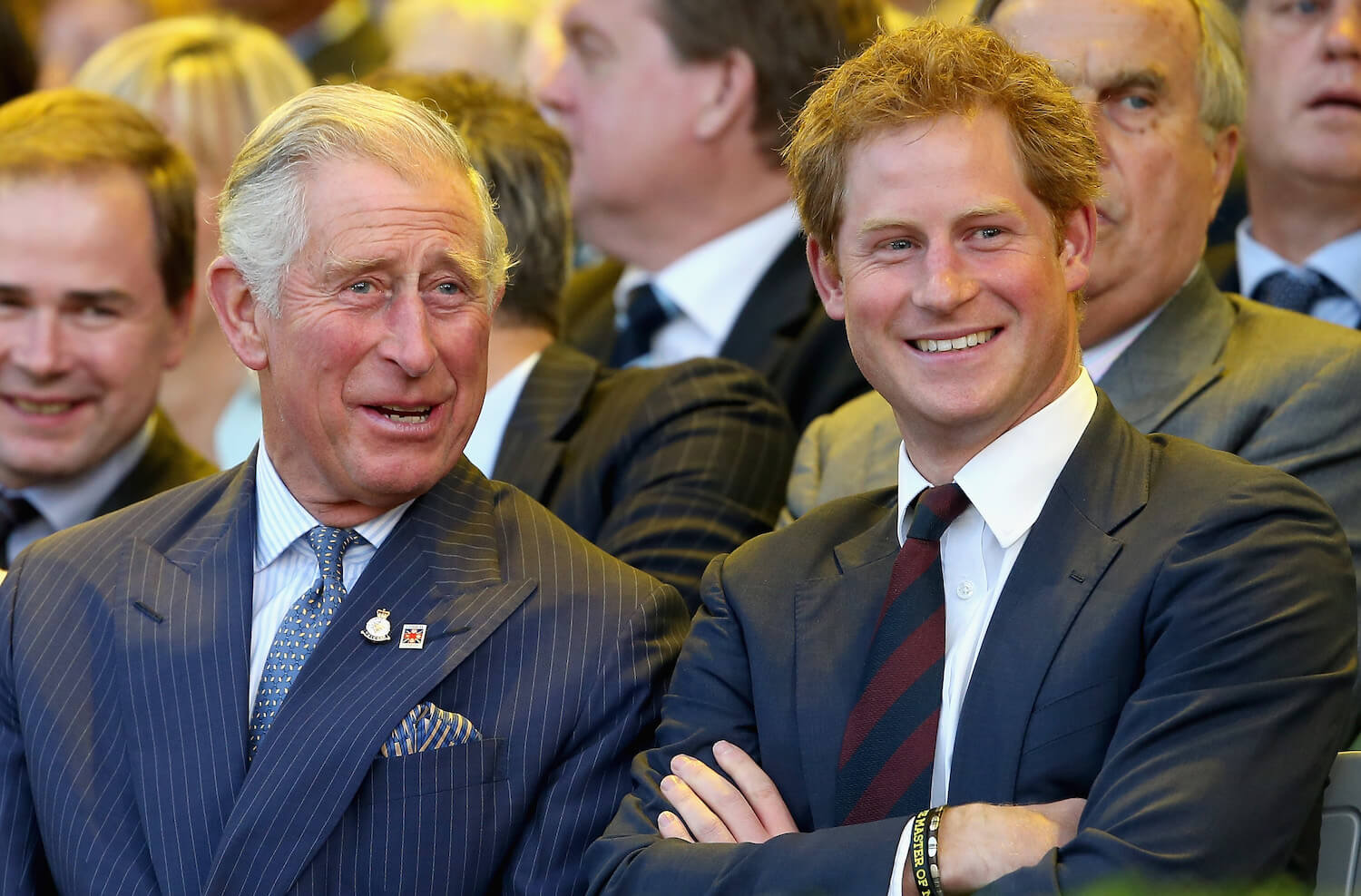 King Charles III and Prince Harry sitting next to each other and talking while smiling