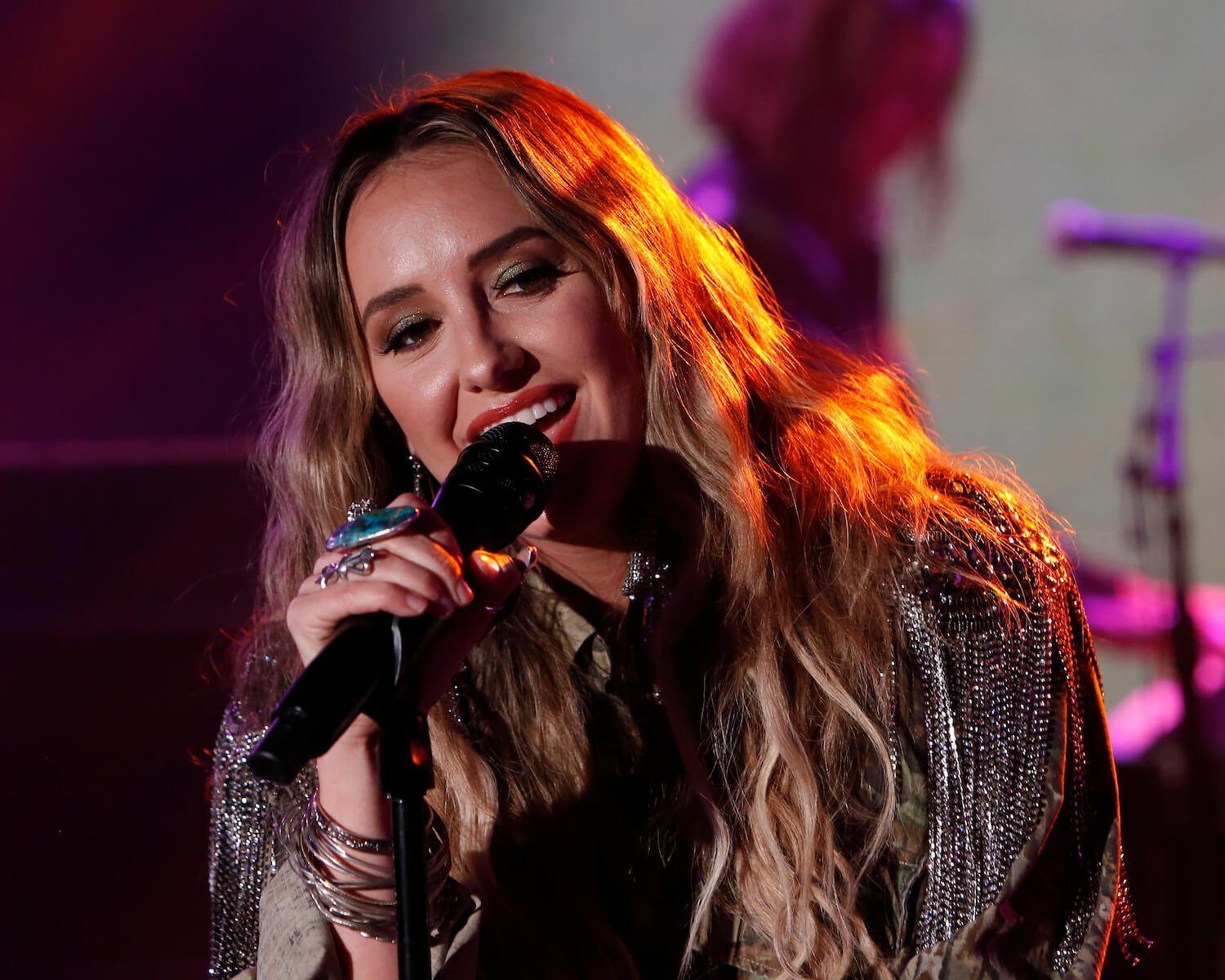 Lainey Wilson from 'Yellowstone' Season 5 singing into a microphone on stage during a talk show