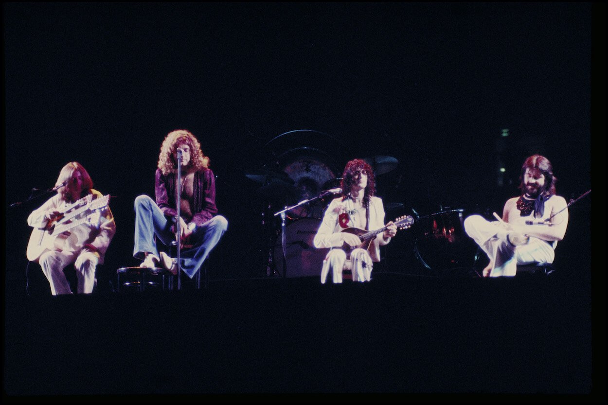 Led Zeppelin members John Paul Jones, Robert Plant, Jimmy Page, and John Bonham seated during a concert.