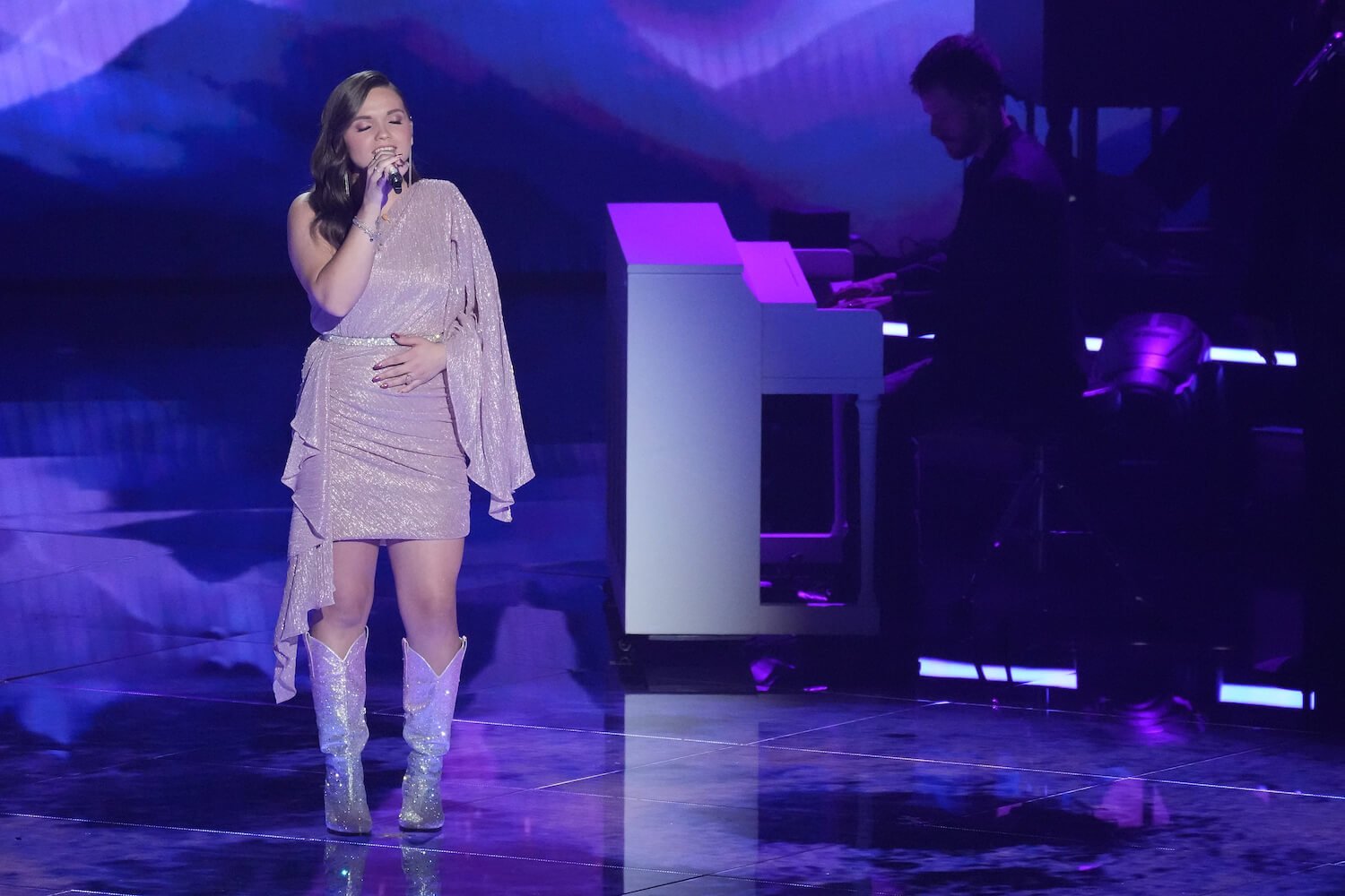 Megan Danielle singing in a dress on the 'American Idol' 2023 stage against a purple background