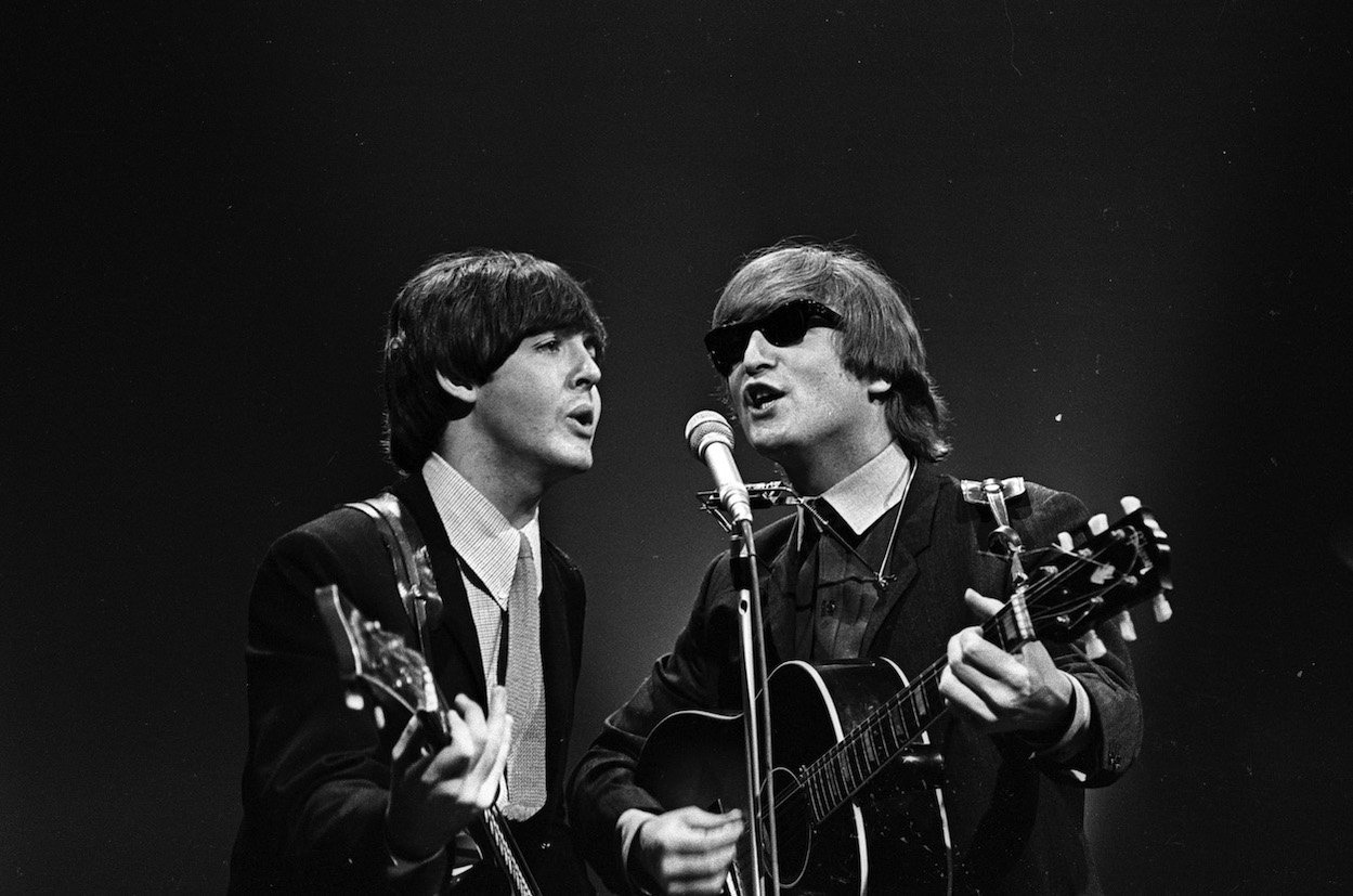 Paul McCartney and John Lennon singing ingot a shared microphone during a 1964 TV appearance.