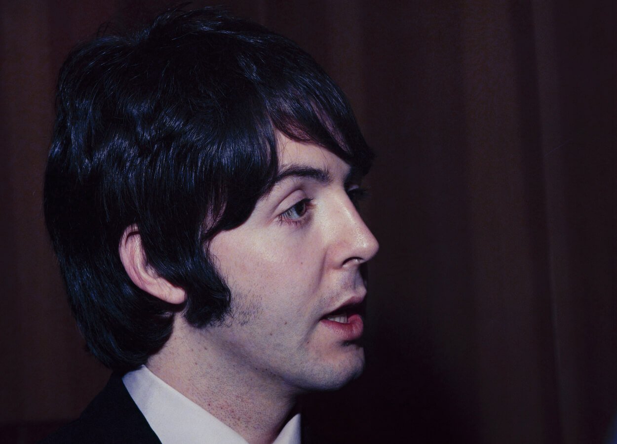 Paul McCartney wearing a collared shirt and looking off in the distance as he speaks.