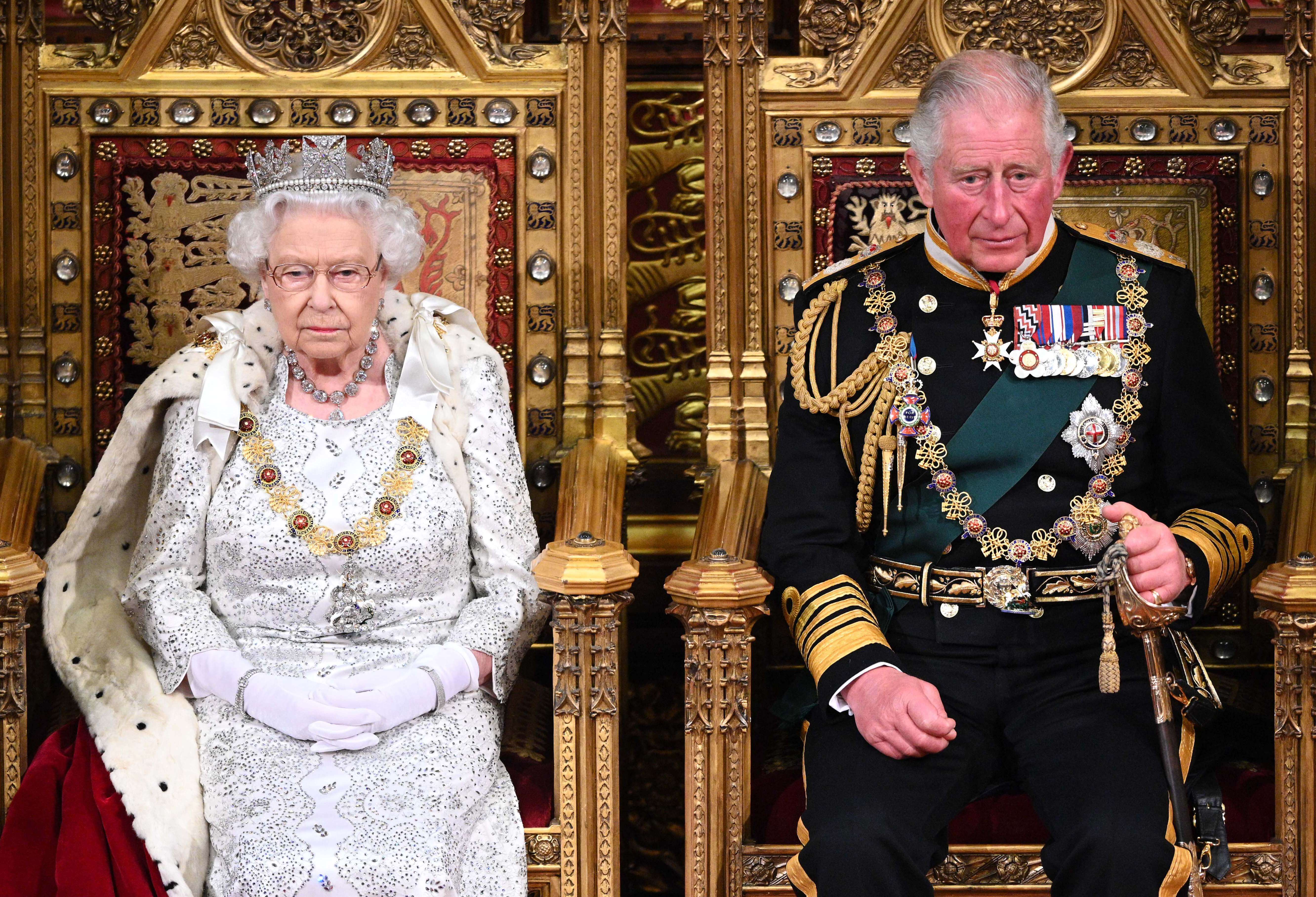 Queen Elizabeth II, whose godson Lord Carnarvon was snubbed from King Charles' coronation, with her son during the State Opening of Parliament