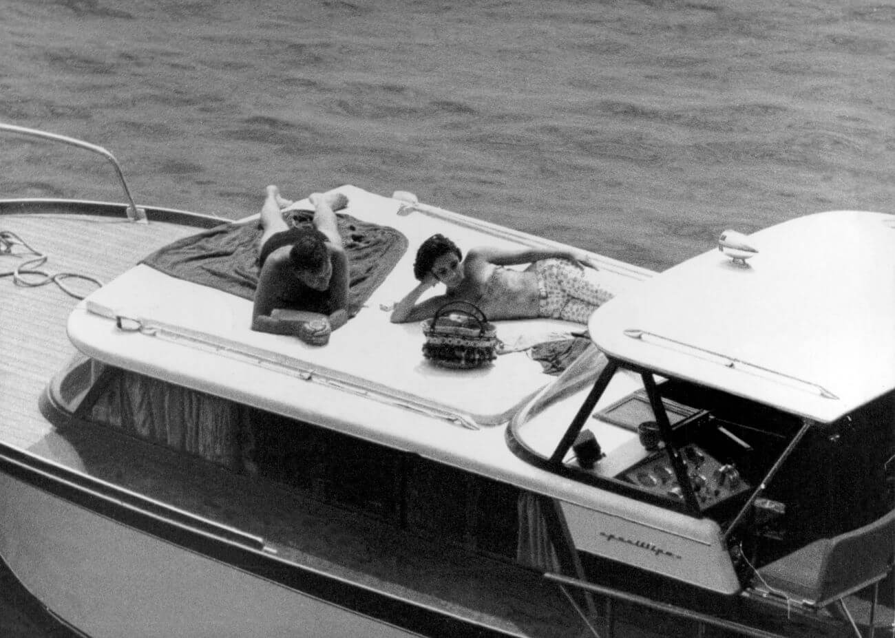 A black and white picture of Richard Burton and Elizabeth Taylor laying on a boat.