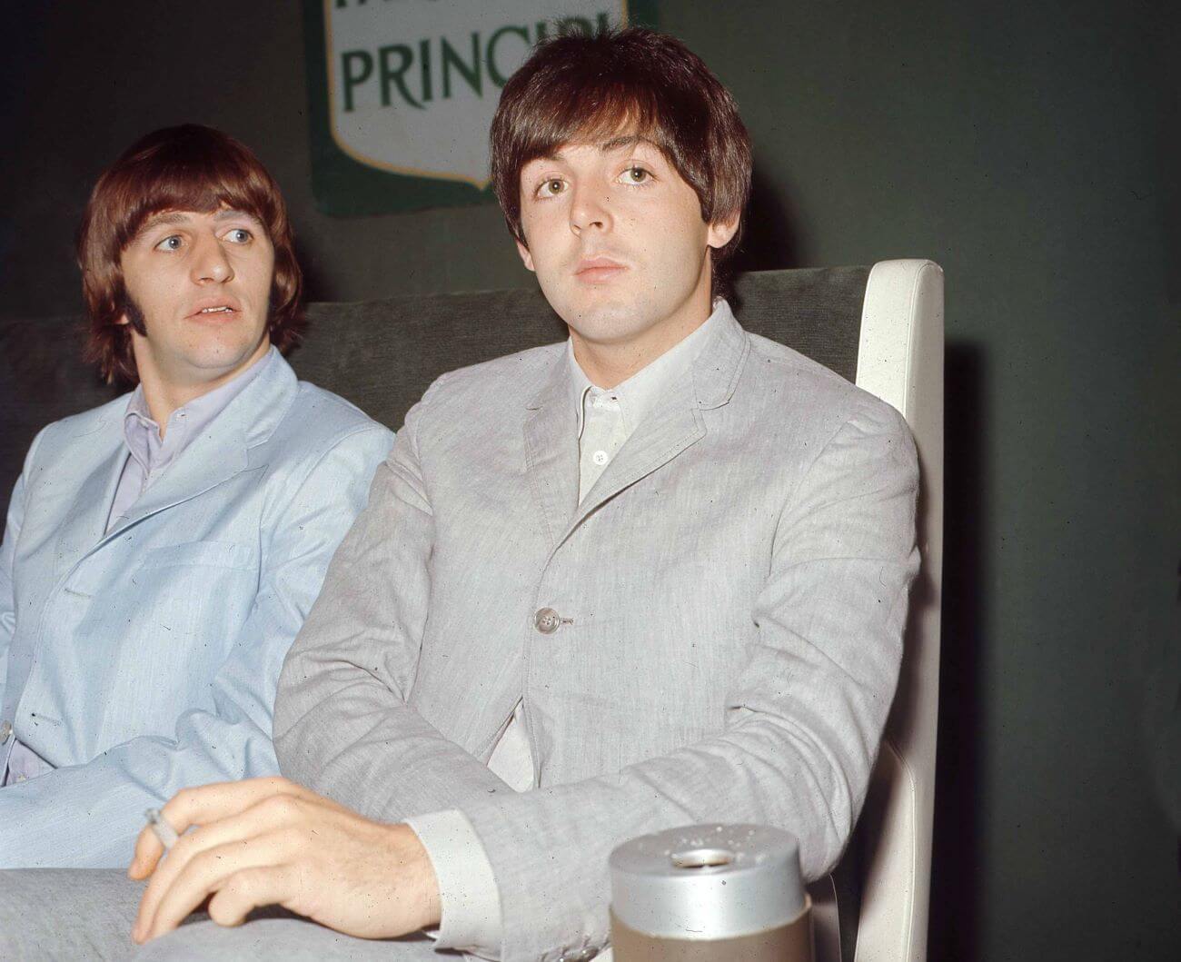 Ringo Starr and Paul McCartney sit next to each other at a table.