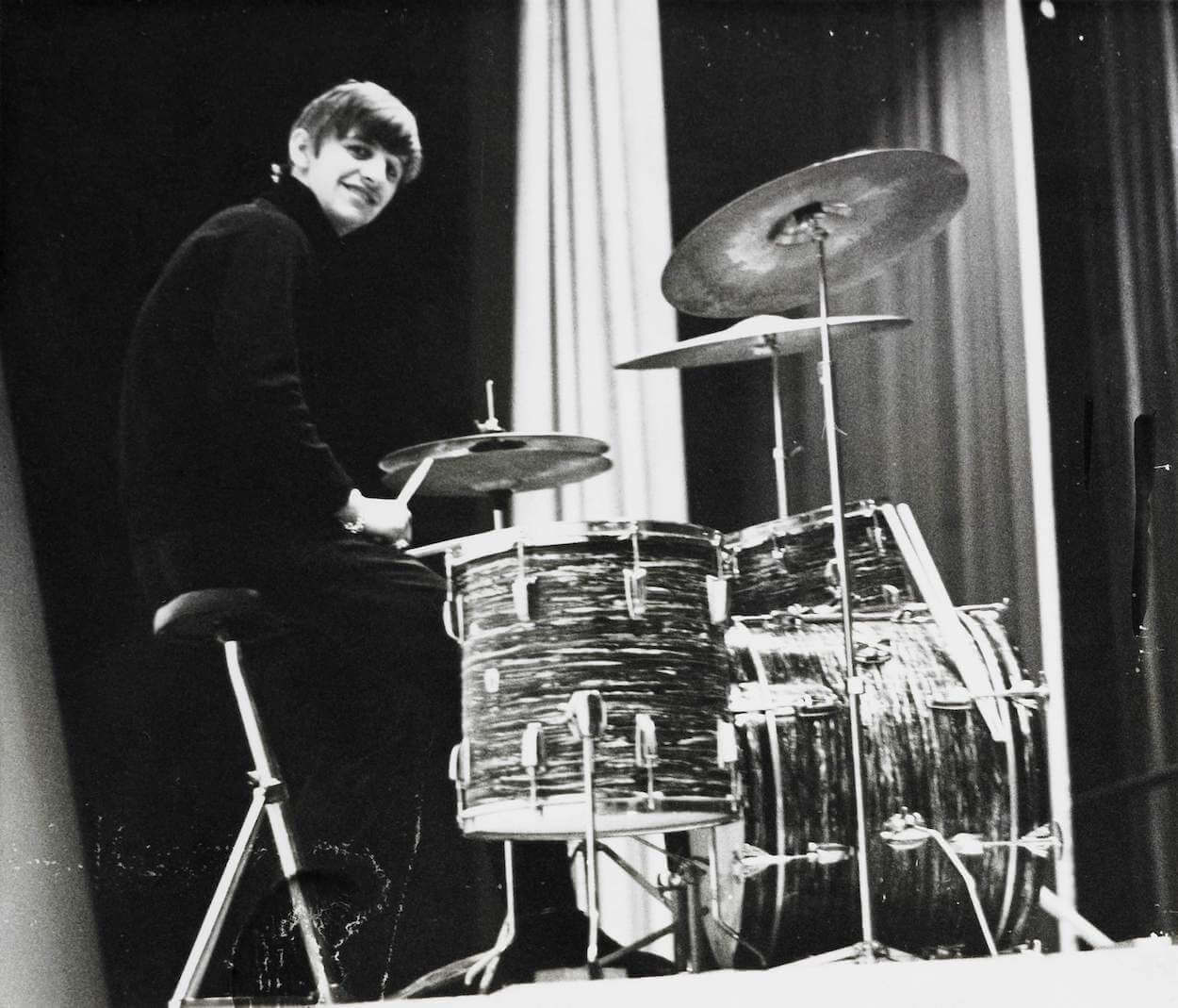 Beatles drummer Ringo Starr sitting behind his kit and smiling at the camera circa 1963.
