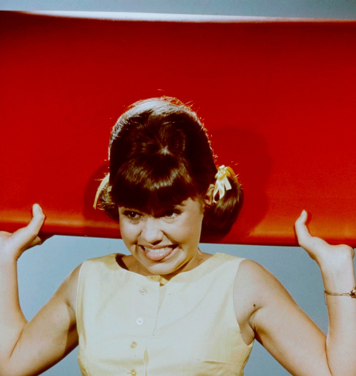 Sally Field poses with a red surf board for promotional material for the TV adaptation of 'Gidget'